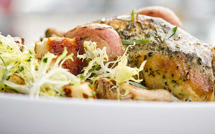 A whole, herb-roasted chicken nestled among frisee.